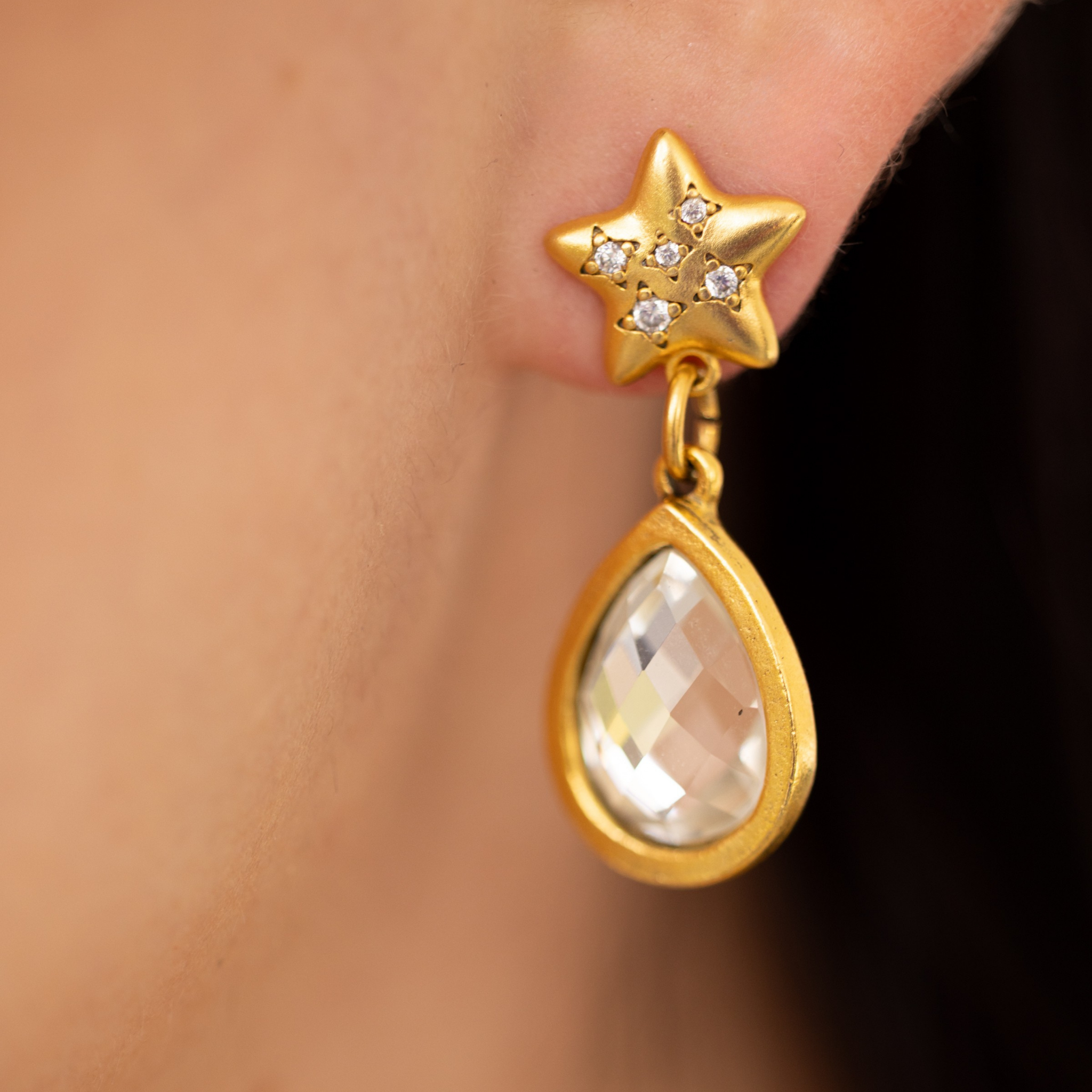 Close-up of Lanamara gold star stud earring with CZ stars and faceted Swarovski teardrop