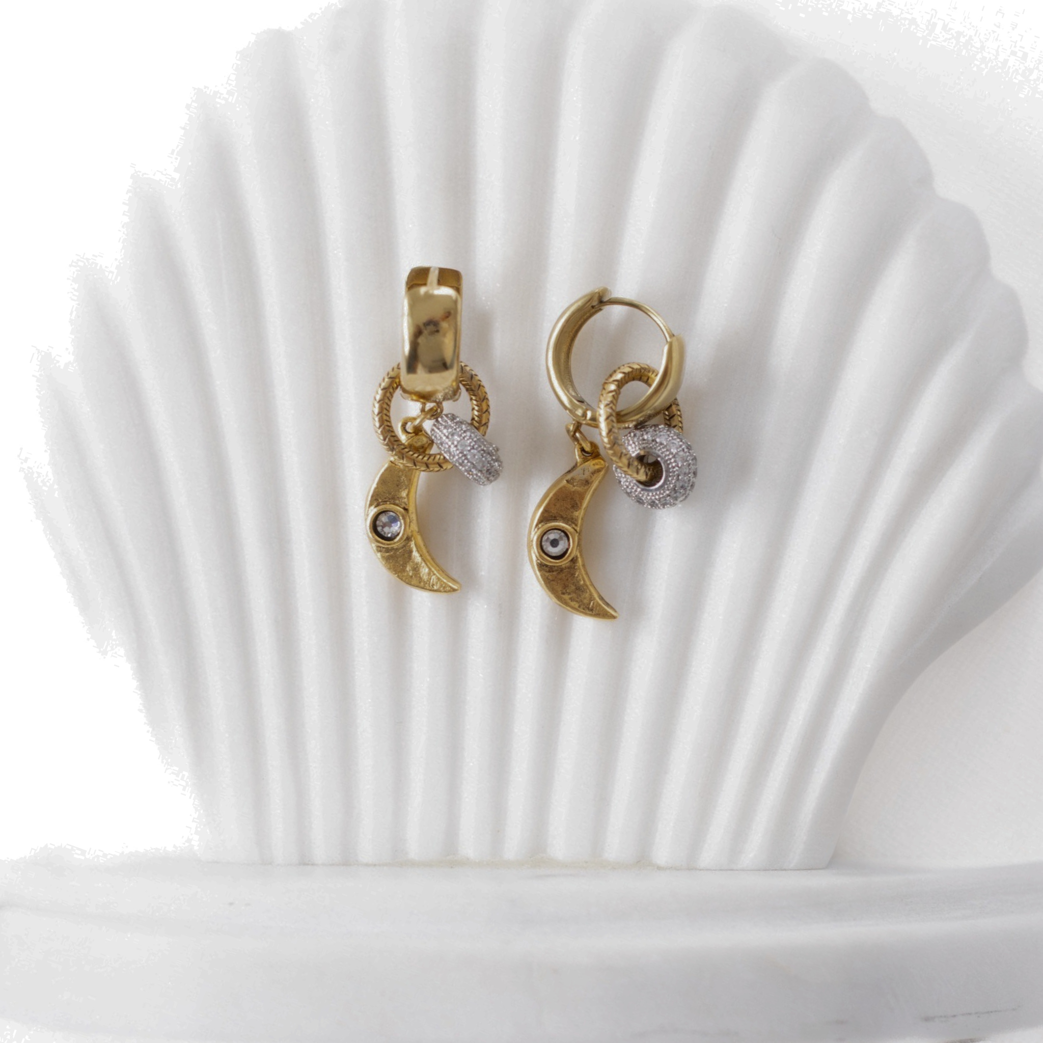 Lanamara Celestial gold crescent moon huggie earrings displayed on a shell stand
