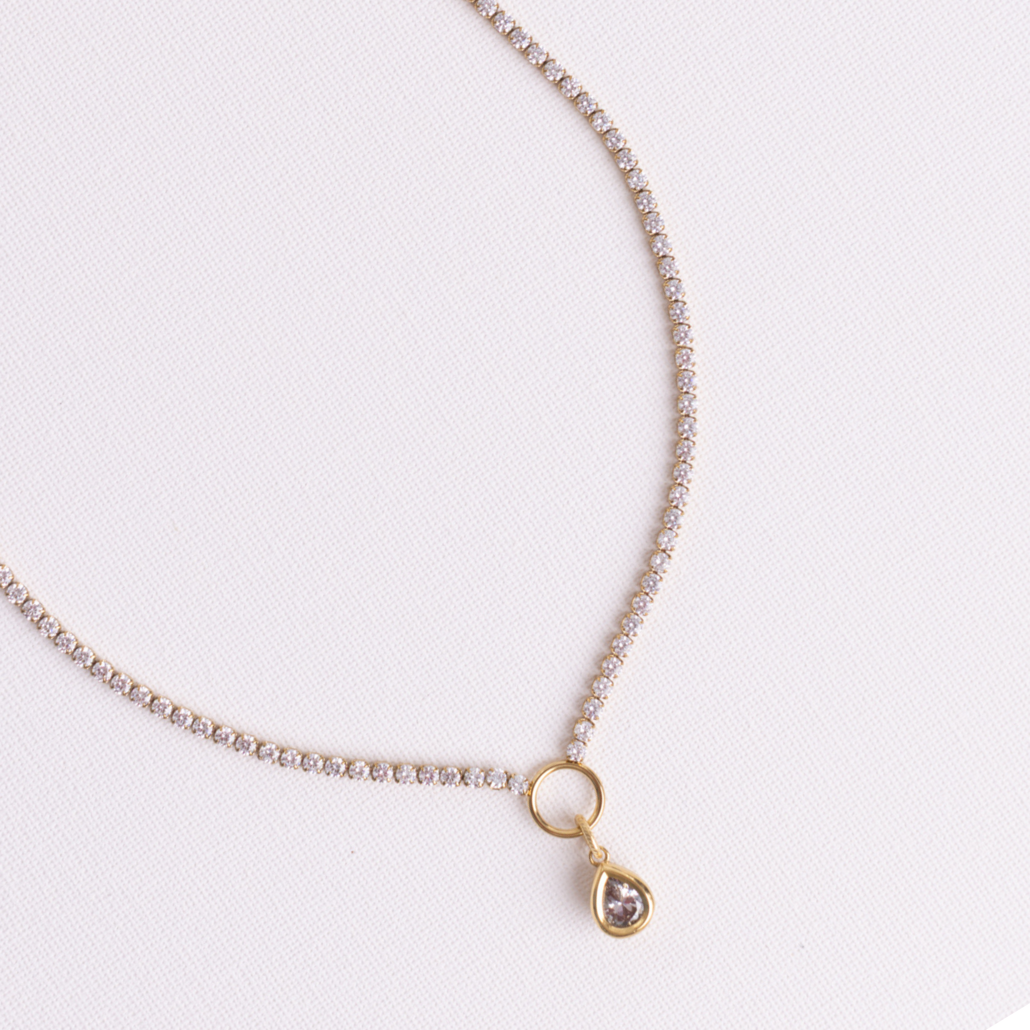 Lanamara Clarity pear tennis necklace with bezel-set pear pendant on O-ring, flat lay