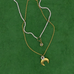 Lanamara Clarity pear tennis necklace layered with the gold crescent moon necklace on green