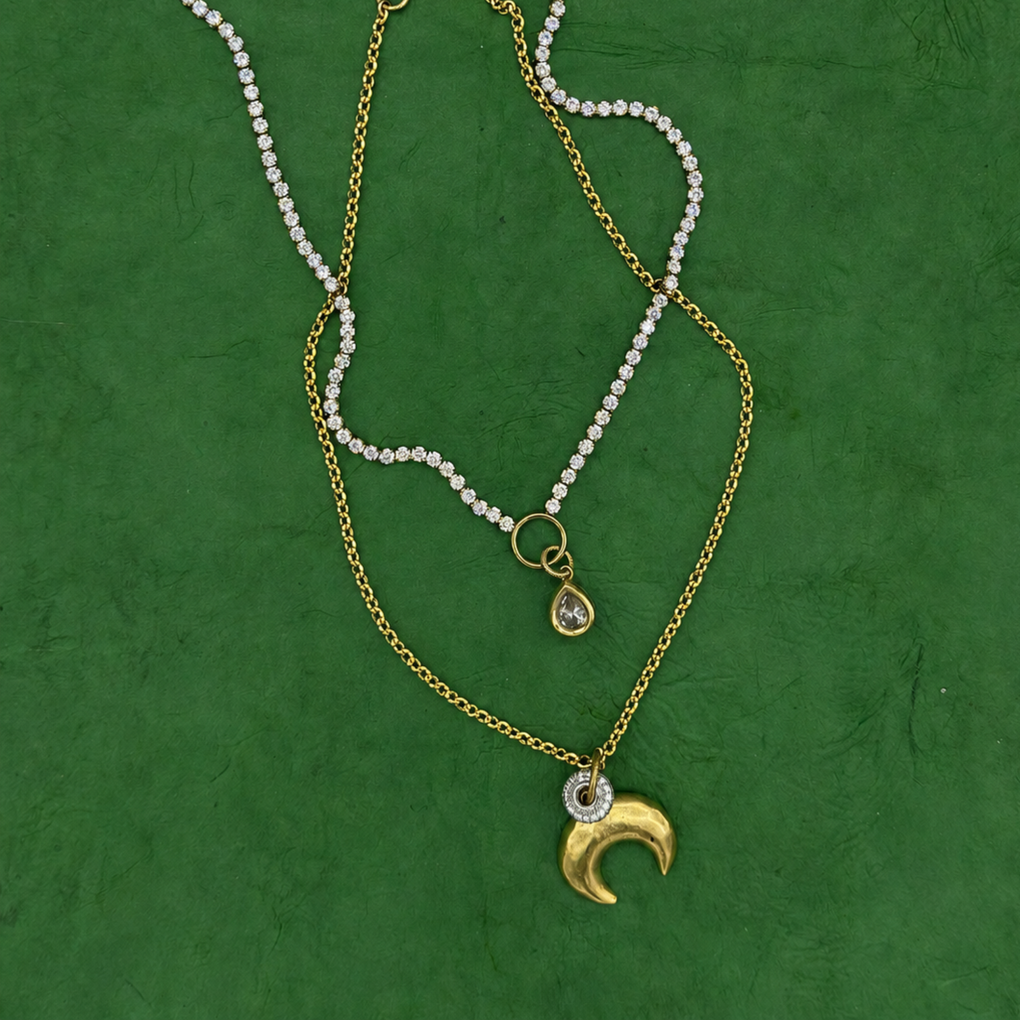 Lanamara Clarity pear tennis necklace layered with the gold crescent moon necklace on green