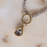 Close-up of Lanamara bezel-set CZ pear pendant on gold tennis necklace