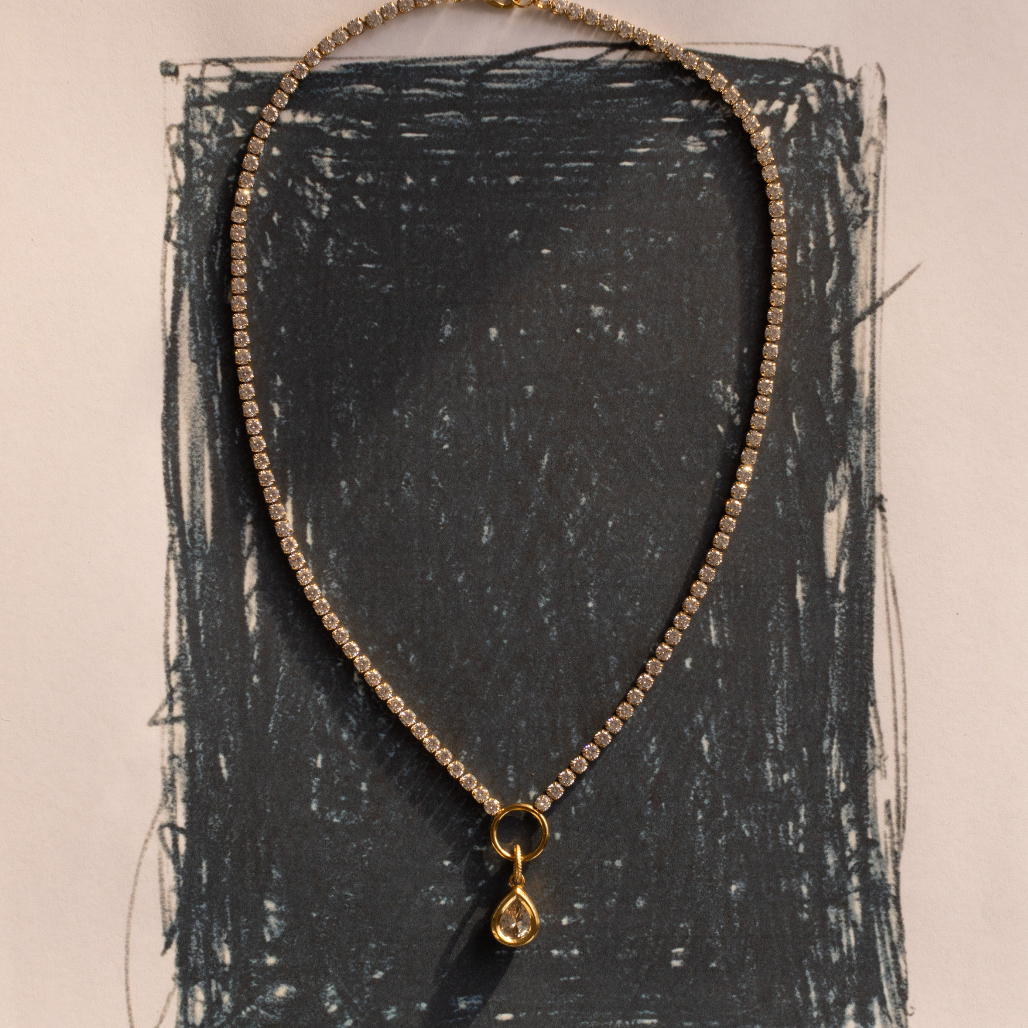 Lanamara Clarity pear tennis necklace styled on an artistic charcoal backdrop