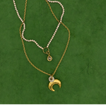 Lanamara Intuition gold crescent moon necklace styled with bezel tennis necklace on green