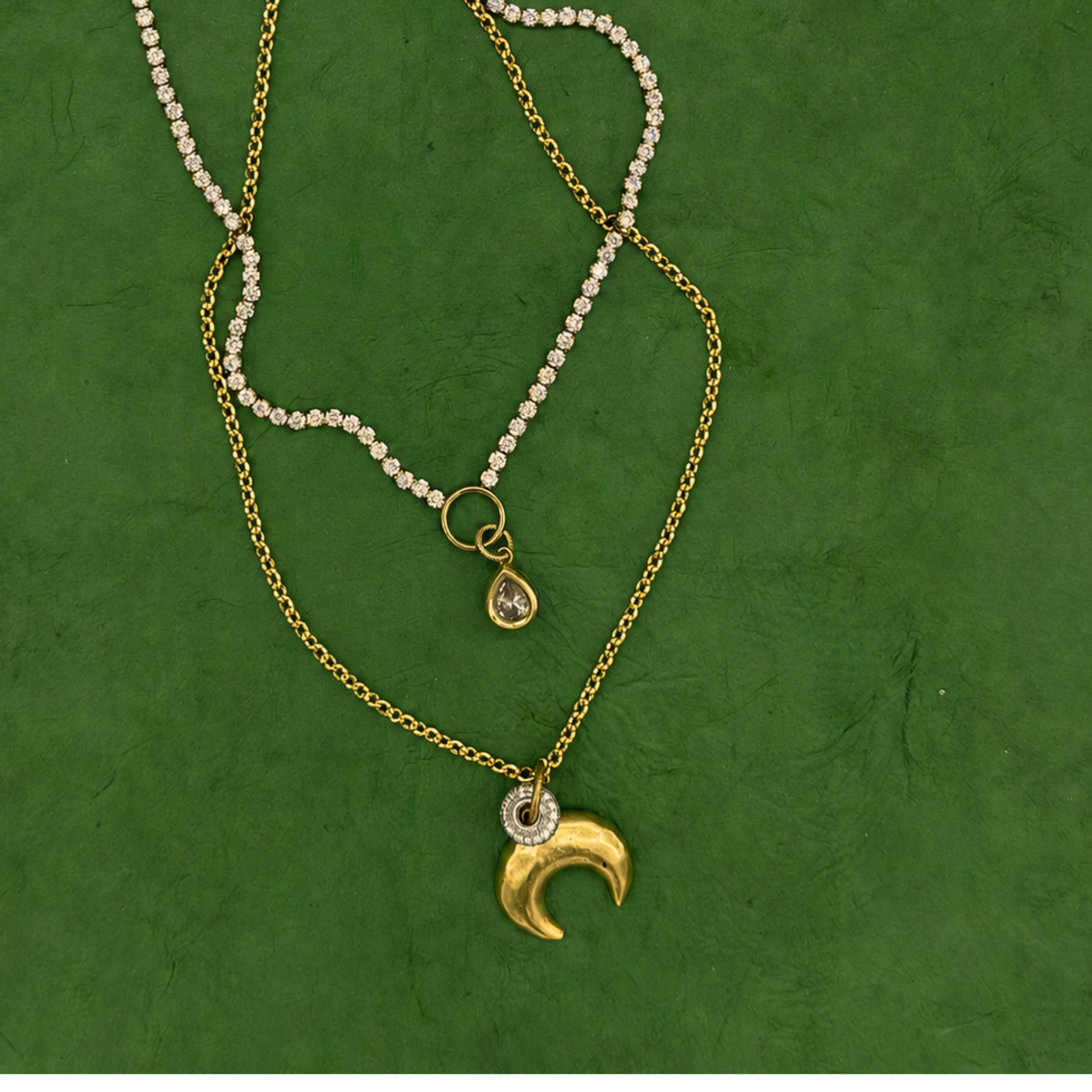 Lanamara Intuition gold crescent moon necklace styled with bezel tennis necklace on green