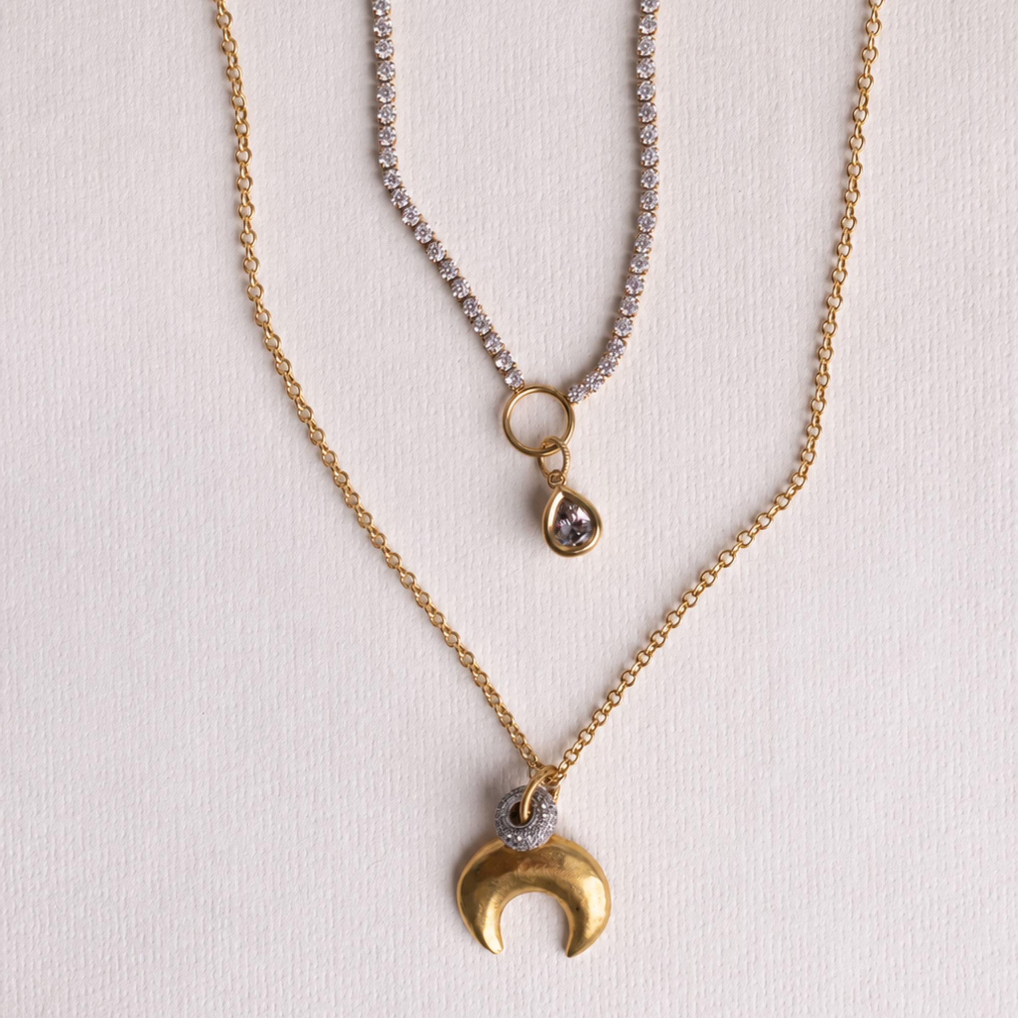 Lanamara Intuition gold crescent moon necklace layered with bezel tennis necklace, flat lay
