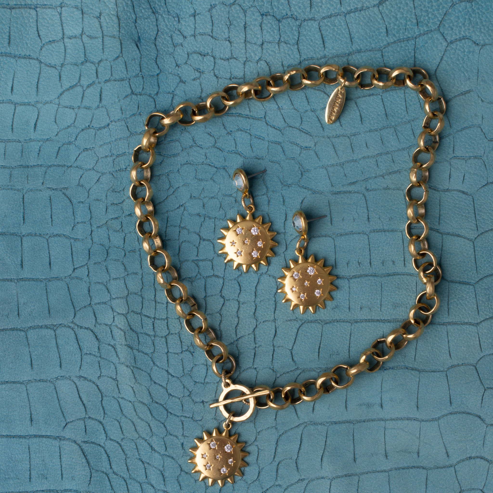 Lanamara Intuition Sunstar earrings with matching sunstar necklace, styled on teal