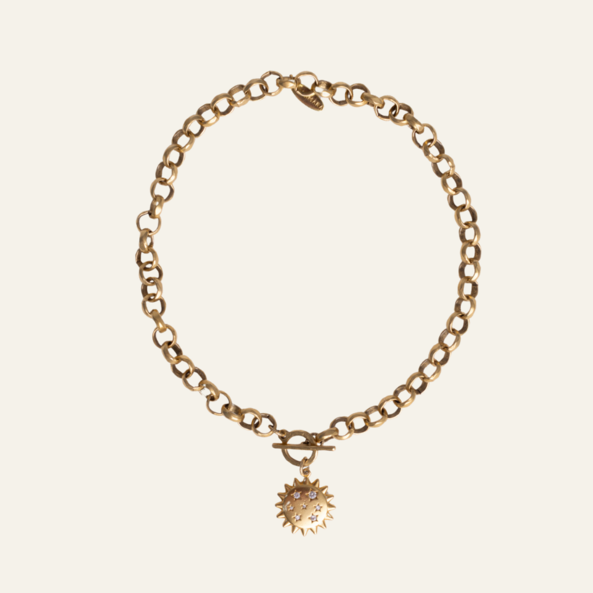 Lanamara Sunstar Necklace — matte gold sun pendant with CZ stars on artisan chain with toggle