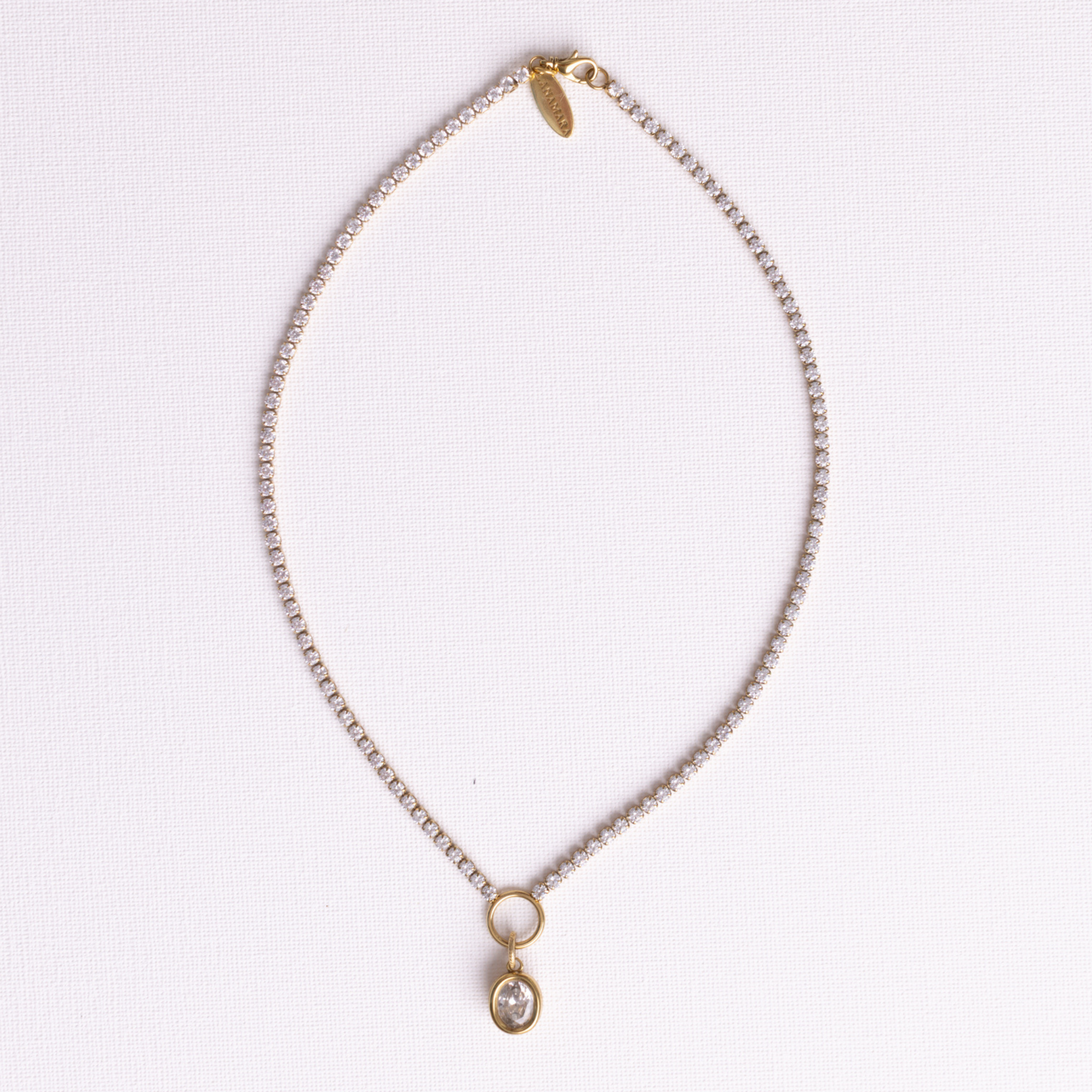 Lanamara Clarity Tennis Necklace – Oval, gold CZ chain with bezel-set oval pendant, flat lay on white