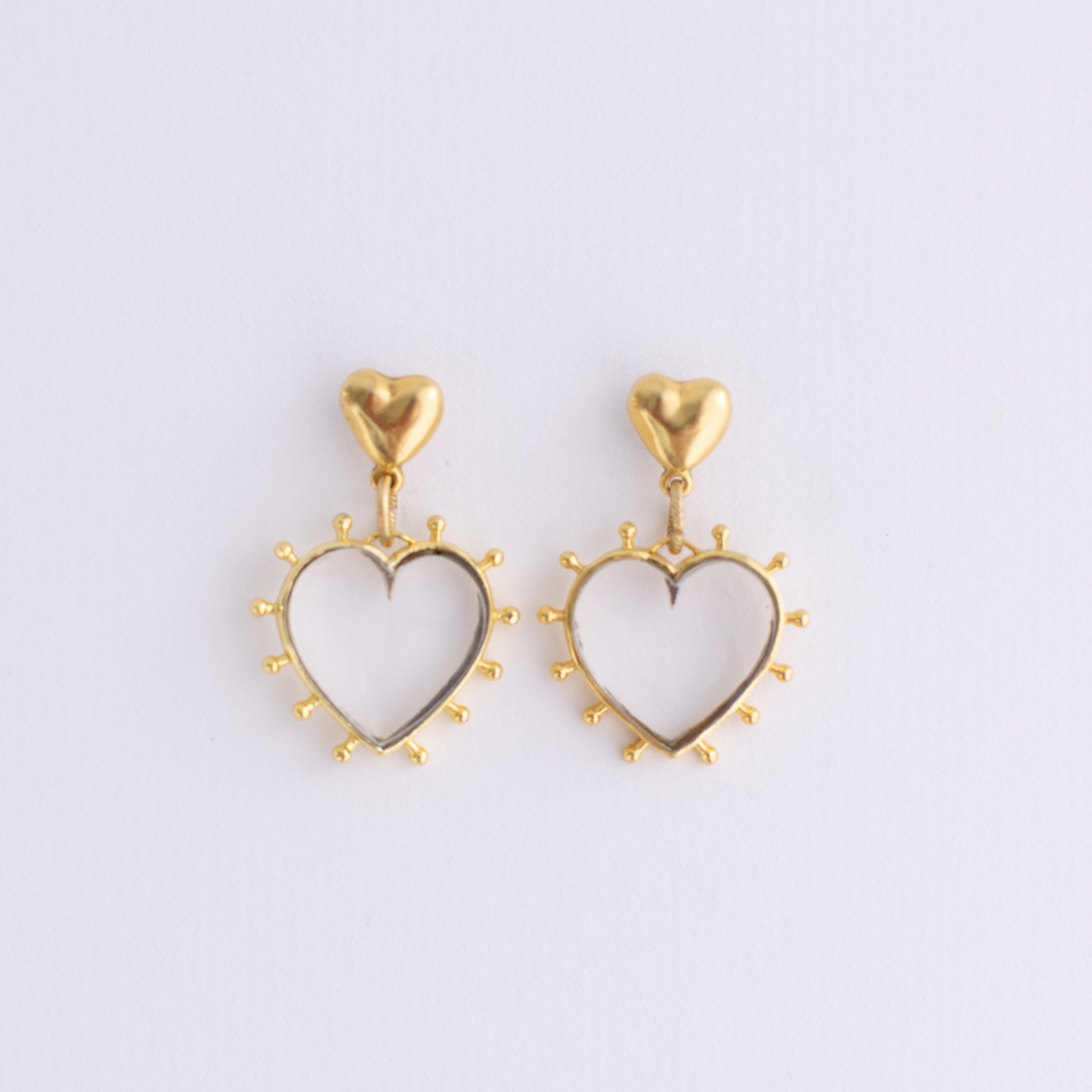 Lanamara open heart drop earrings in gold with a radiant beaded edge on a soft lilac background
