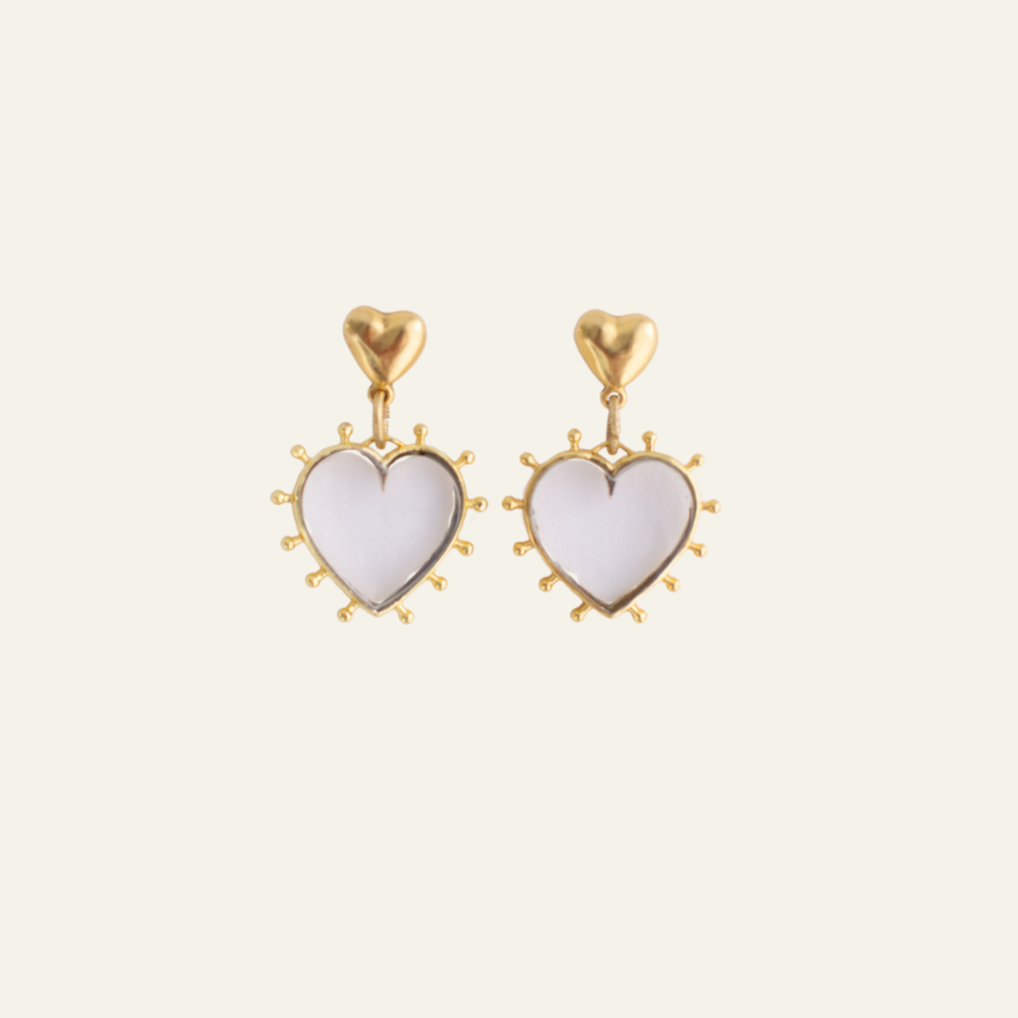 Lanamara Open Hearted clear quartz and gold heart drop earrings on a cream background