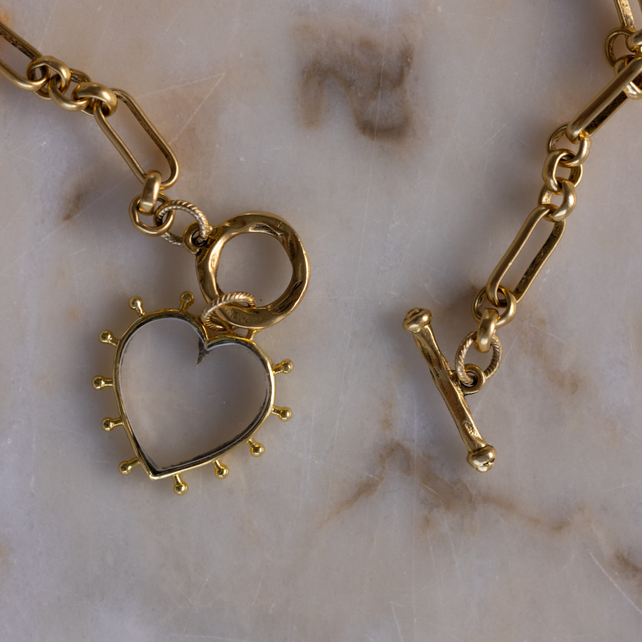 Close-up of Lanamara clear quartz open heart pendant with gold beaded edging and toggle