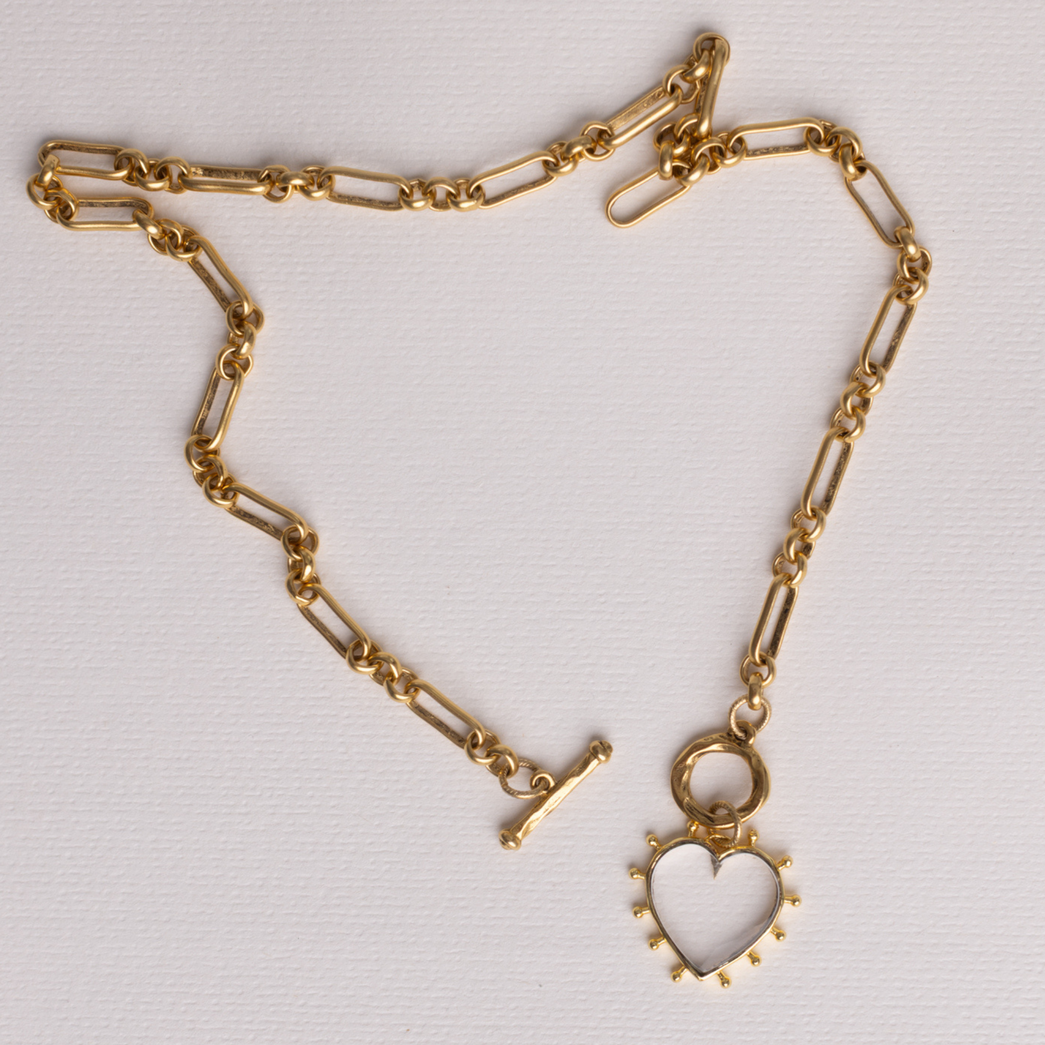 Full length of Lanamara Open Hearted gold heirloom chain necklace with clear quartz heart, flat lay